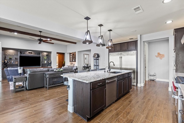 kitchen with a kitchen island with sink, decorative light fixtures, stainless steel appliances, and dark brown cabinetry