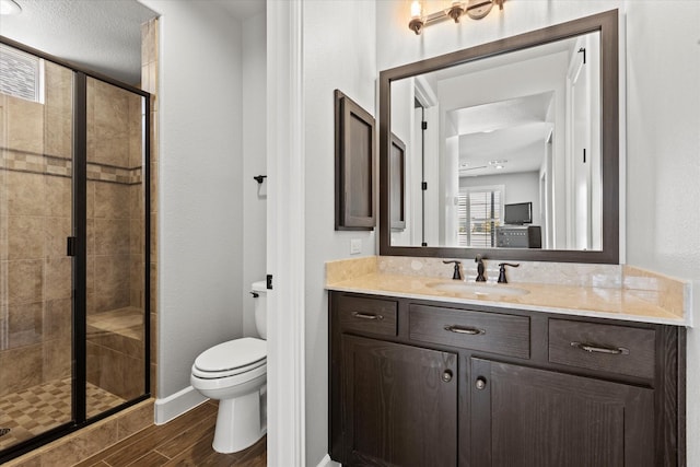 bathroom with wood-type flooring, vanity, an enclosed shower, toilet, and a textured ceiling