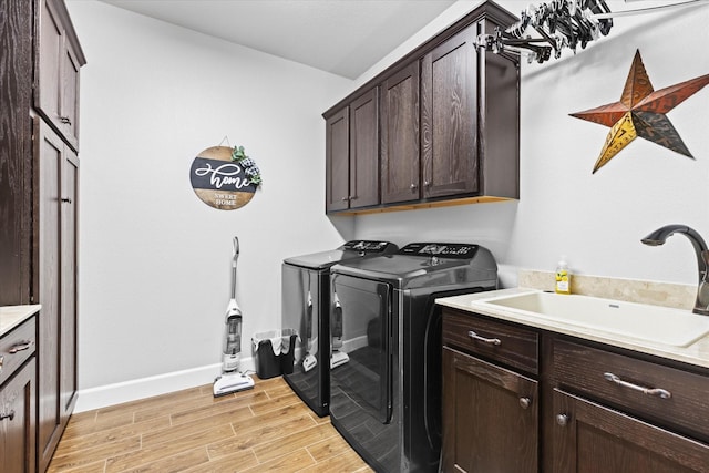 laundry room featuring light hardwood / wood-style floors, cabinets, washer and clothes dryer, and sink