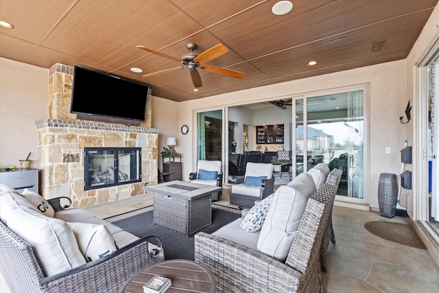 view of patio / terrace with ceiling fan and an outdoor living space with a fireplace