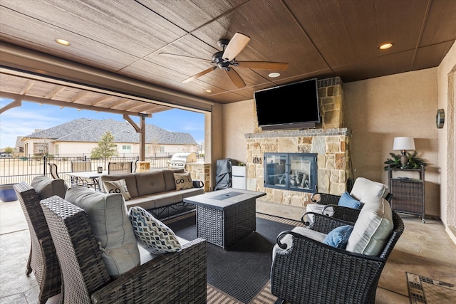 view of patio with ceiling fan, an outdoor living space with a fireplace, and exterior kitchen