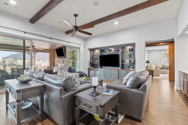 living room featuring beamed ceiling, light wood-type flooring, and ceiling fan