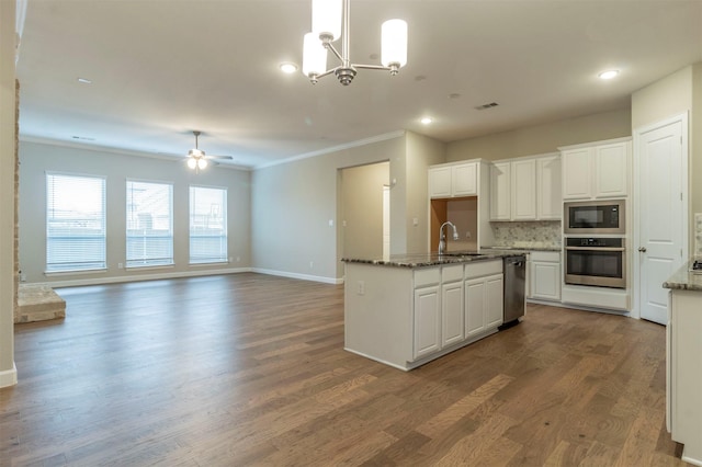 kitchen with sink, white cabinetry, dark stone countertops, black microwave, and stainless steel oven