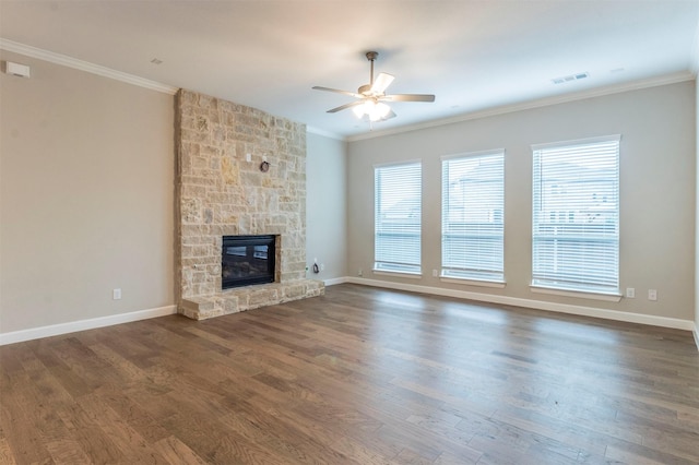 unfurnished living room featuring dark hardwood / wood-style floors, ceiling fan, ornamental molding, and a stone fireplace