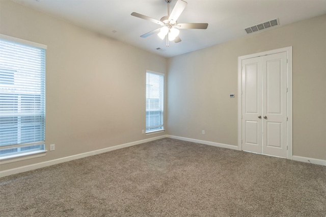 empty room featuring ceiling fan and carpet