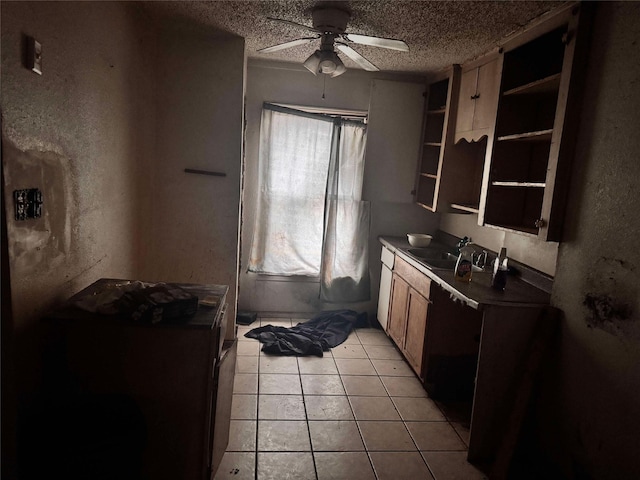 kitchen with ceiling fan, sink, light tile patterned floors, and a textured ceiling