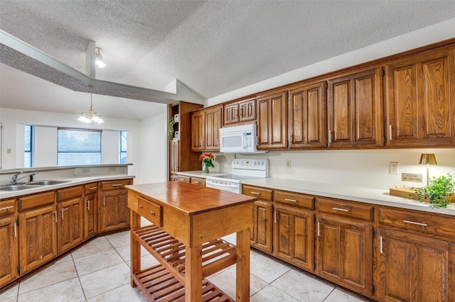 kitchen featuring decorative light fixtures, lofted ceiling, sink, white appliances, and an inviting chandelier