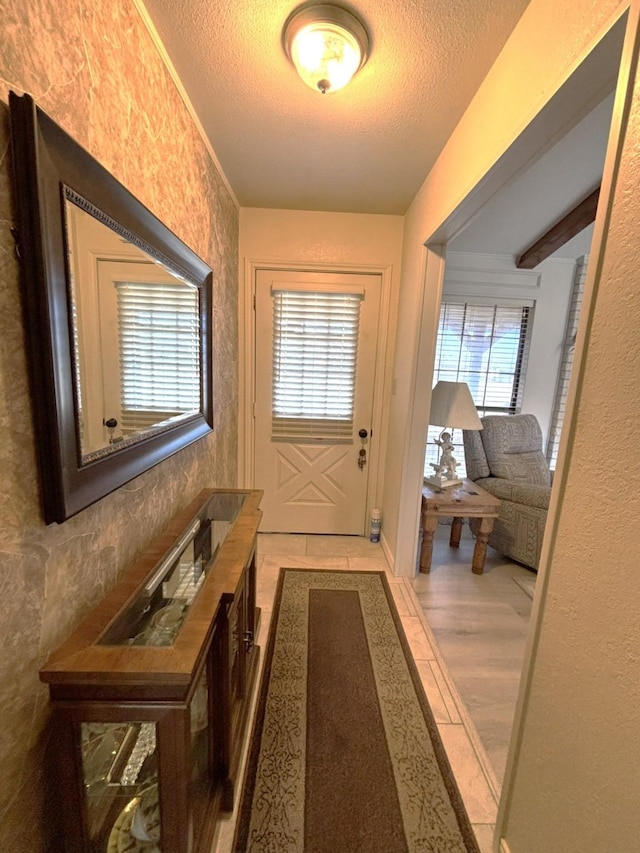 entryway with light hardwood / wood-style flooring, beamed ceiling, and a textured ceiling