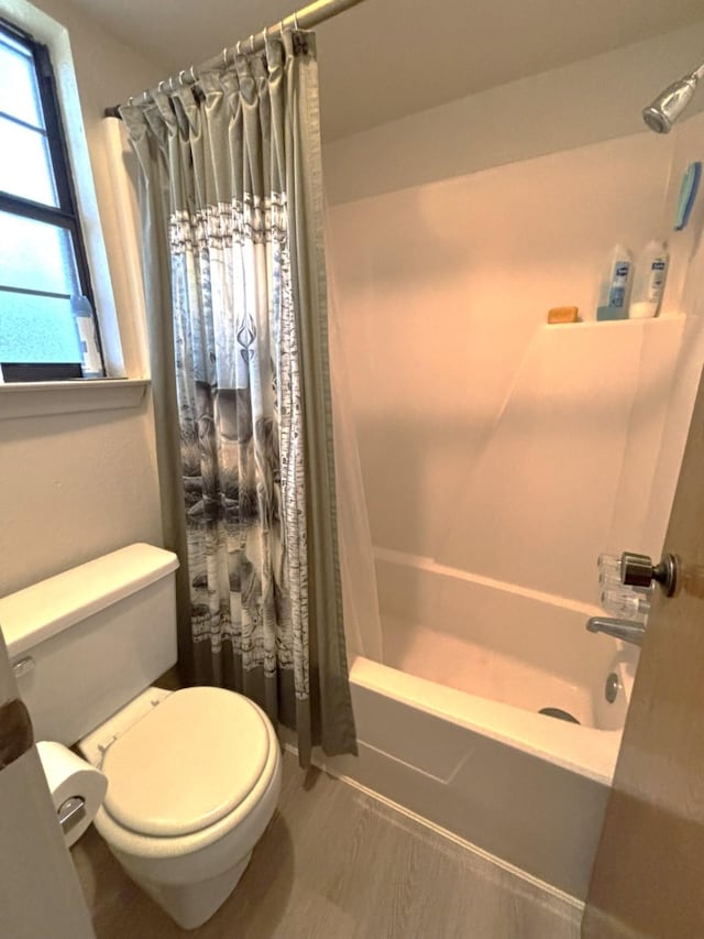 bathroom with toilet, wood-type flooring, and shower / bathtub combination with curtain