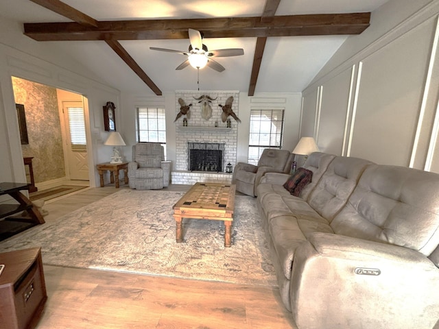 living room featuring a fireplace, lofted ceiling with beams, light hardwood / wood-style floors, and ceiling fan