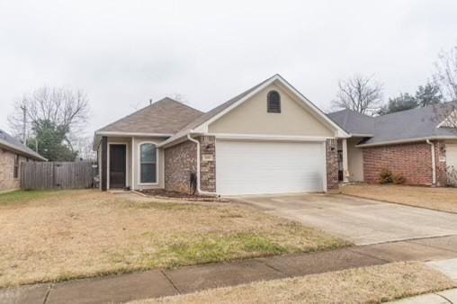 ranch-style house with a garage and a front lawn