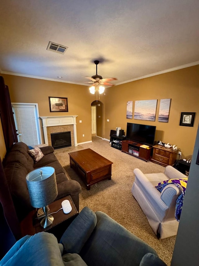 carpeted living room featuring a fireplace, ornamental molding, and ceiling fan