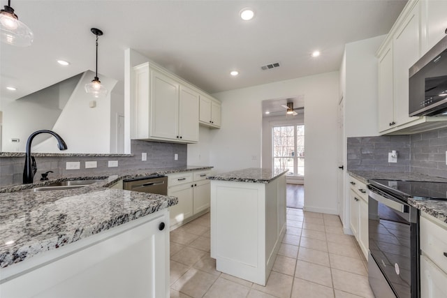 kitchen with stainless steel appliances, light stone countertops, sink, and hanging light fixtures