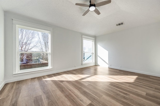 empty room with hardwood / wood-style flooring, ceiling fan, and a textured ceiling