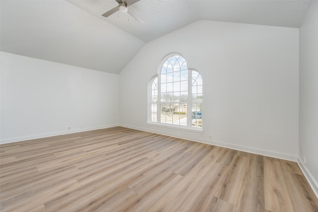 interior space with a textured ceiling, vaulted ceiling, ceiling fan, and light wood-type flooring