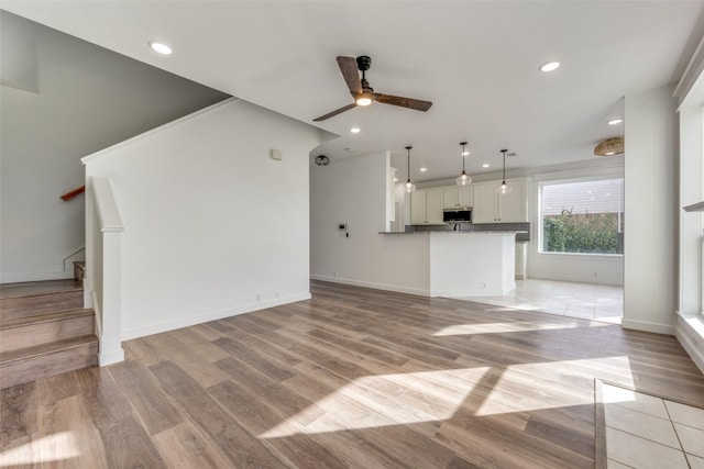 unfurnished living room featuring ceiling fan and light hardwood / wood-style floors