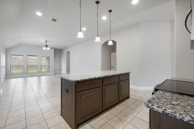 kitchen featuring light tile patterned flooring, decorative light fixtures, vaulted ceiling, a kitchen island, and ceiling fan