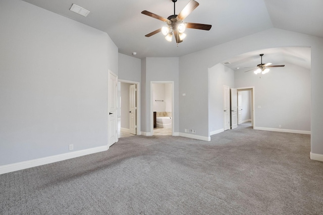 carpeted empty room featuring a ceiling fan, visible vents, baseboards, arched walkways, and lofted ceiling
