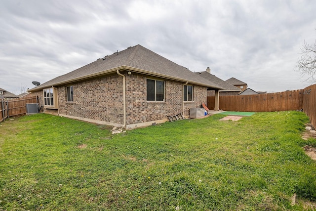 back of house with brick siding, a fenced backyard, cooling unit, and a yard