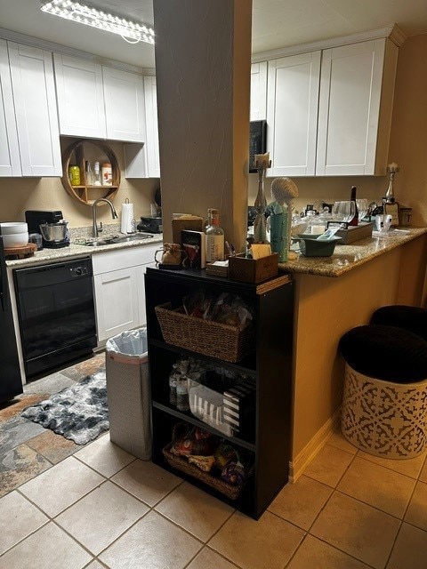 kitchen featuring sink, light tile patterned floors, black dishwasher, and white cabinets