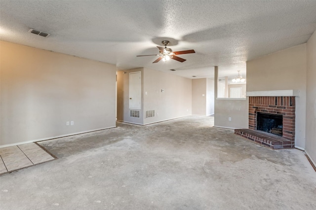 unfurnished living room with ceiling fan with notable chandelier, a textured ceiling, a fireplace, and concrete floors