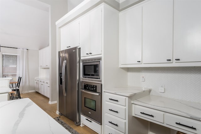 kitchen featuring light stone counters, white cabinetry, appliances with stainless steel finishes, and light wood-type flooring