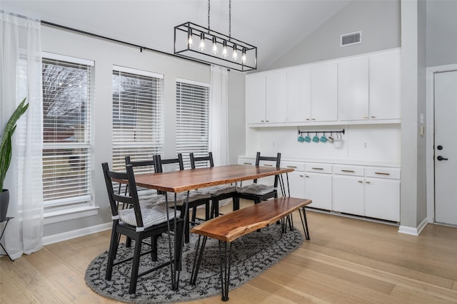 dining room with high vaulted ceiling and light wood-type flooring