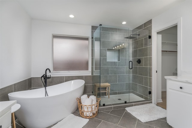 bathroom with vanity, tile patterned flooring, tile walls, and separate shower and tub