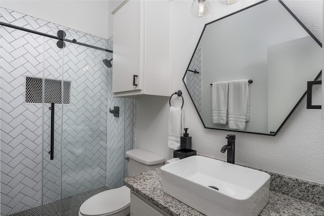 bathroom featuring vanity, a shower with shower door, and toilet