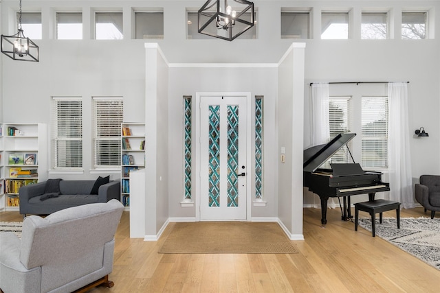 foyer entrance featuring an inviting chandelier, a high ceiling, and light wood-type flooring