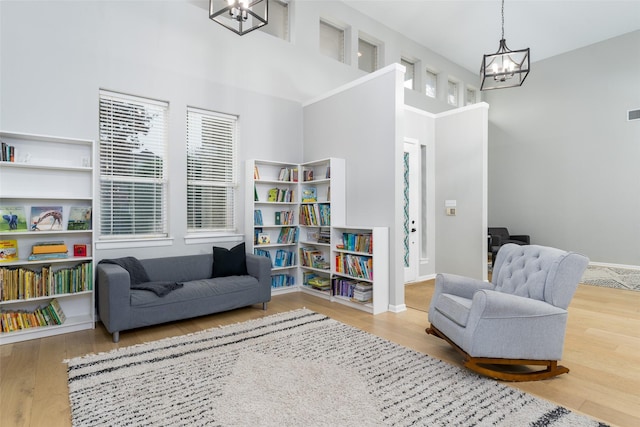 sitting room with hardwood / wood-style flooring, a high ceiling, and a notable chandelier