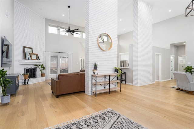 living room with a wealth of natural light, a fireplace, ceiling fan, and light hardwood / wood-style flooring