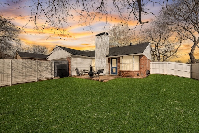 back house at dusk with a yard and a patio