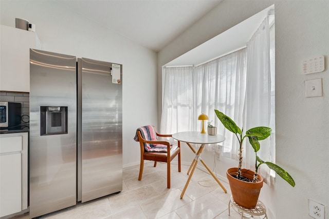 kitchen with white cabinetry, lofted ceiling, appliances with stainless steel finishes, and light tile patterned flooring