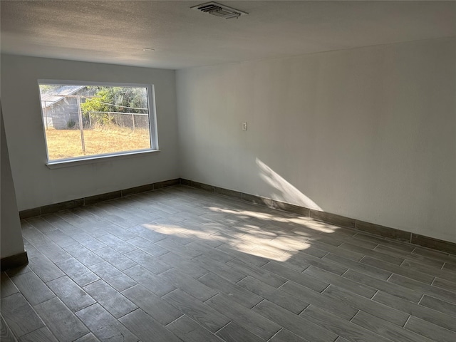 spare room featuring baseboards, visible vents, and wood finish floors