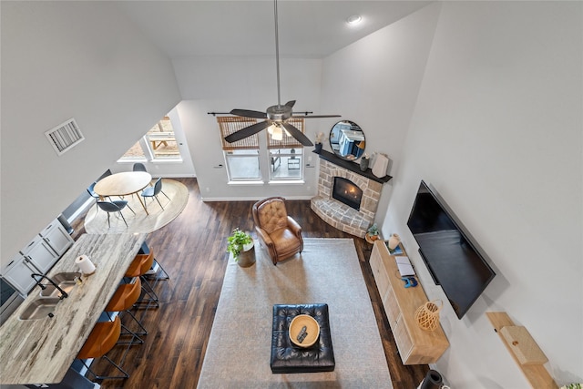 living room with a fireplace, lofted ceiling, sink, dark hardwood / wood-style flooring, and ceiling fan