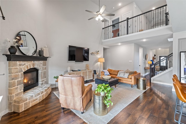 living room with a towering ceiling, a fireplace, dark hardwood / wood-style floors, and ceiling fan