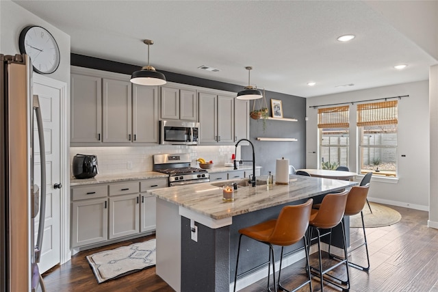 kitchen featuring pendant lighting, sink, a kitchen island with sink, and appliances with stainless steel finishes