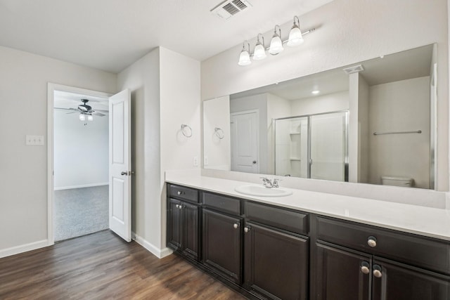 bathroom featuring vanity, hardwood / wood-style floors, walk in shower, and toilet