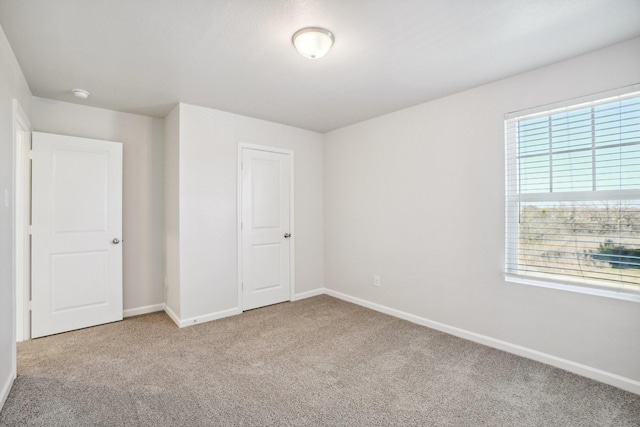 unfurnished bedroom featuring light carpet and multiple windows