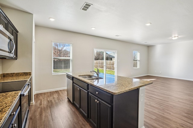 kitchen featuring dark hardwood / wood-style floors, plenty of natural light, stainless steel appliances, and an island with sink