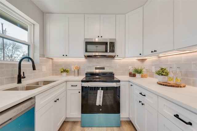 kitchen featuring tasteful backsplash, sink, white cabinets, stainless steel appliances, and light hardwood / wood-style flooring