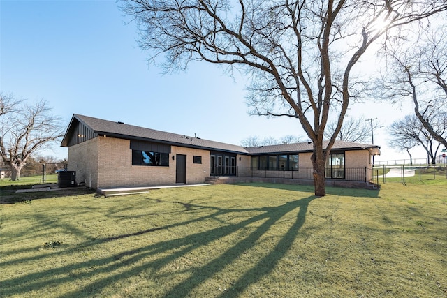 back of property with central AC unit and a lawn