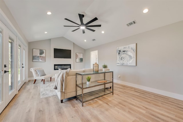 living room featuring ceiling fan, lofted ceiling, and light wood-type flooring