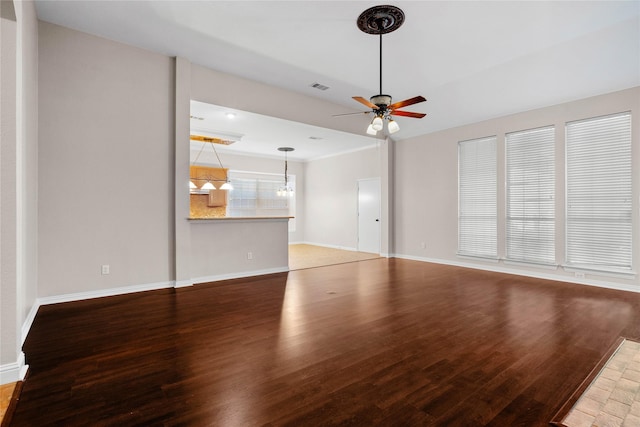 unfurnished living room with ceiling fan with notable chandelier and hardwood / wood-style floors