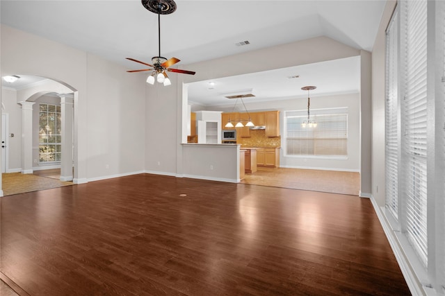 unfurnished living room with ceiling fan with notable chandelier, ornamental molding, and dark hardwood / wood-style floors