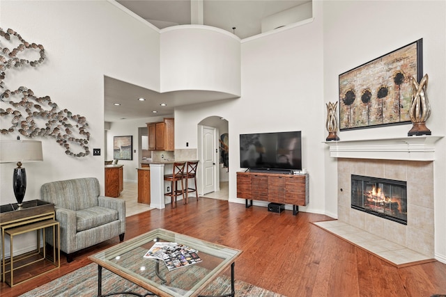 living room with a high ceiling, a tile fireplace, and dark hardwood / wood-style floors