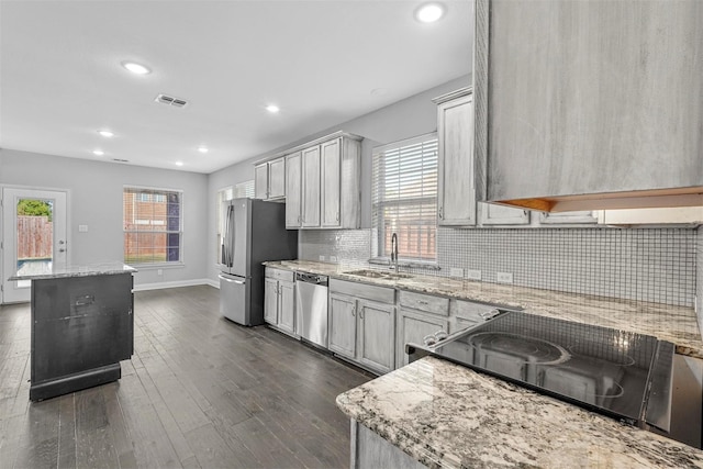 kitchen with light stone counters, sink, a kitchen island, and appliances with stainless steel finishes