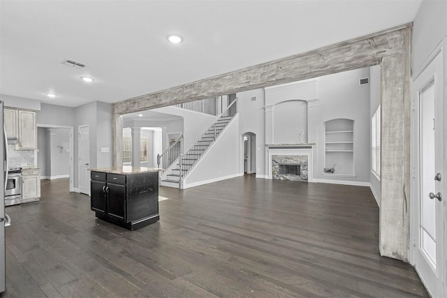 kitchen featuring stainless steel electric range, a kitchen island, a premium fireplace, dark wood-type flooring, and built in shelves