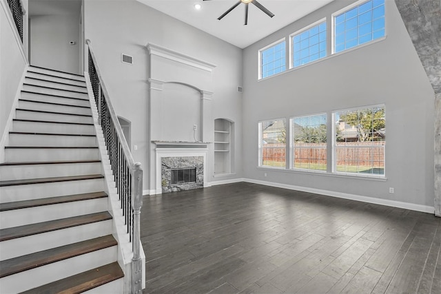 unfurnished living room with plenty of natural light, dark hardwood / wood-style floors, and ceiling fan